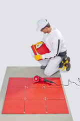 Worker Cuts red Ceramic Tile with Machine Tiling