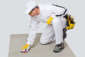 Construction worker with sand paper cleans cement substrate