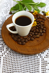 Espresso cup and coffee beans with daisy flower on wooden dish