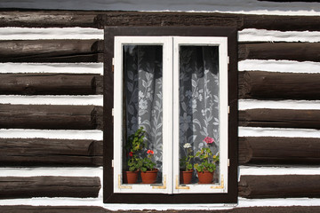 window with flowers in wall of old wooden house