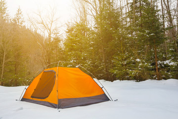 orange touristic tent in a winter forest