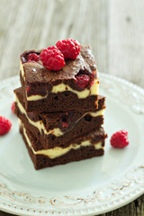 Cheesecake brownies with raspberry stacked on a plate