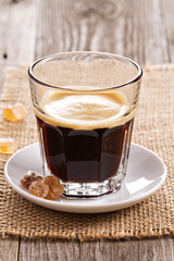 Black coffee in a glass with brown sugar crystals