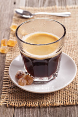 Black coffee in a glass with crystal sugar