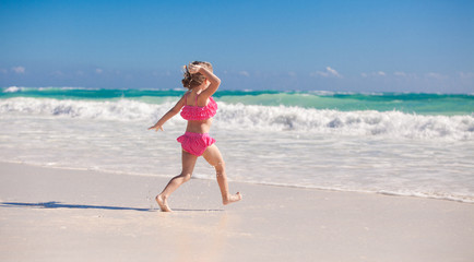Fototapeta na wymiar Little cute girl running on the white sandy beach in Mexico
