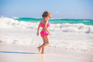 Fototapeta na wymiar Little cute girl walking on the white sandy beach in Mexico