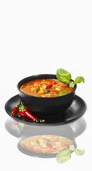 Tomato soup decorated with basil leaf on white background. Copy