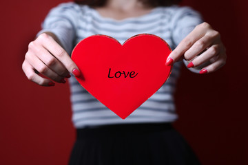 Valentine heart on red background in hands