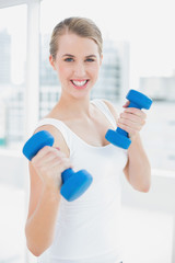 Sporty smiling woman exercising with dumbbells