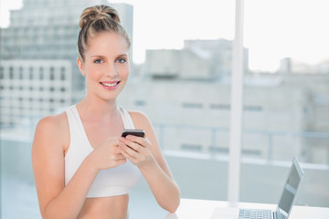 Cheerful sporty blonde sending a text