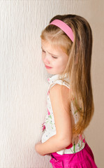 Naughty little girl is standing in the corner