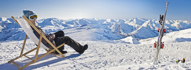 Fototapeta Jeune femme se relaxant dans une chaise sur les pistes de ski, panorama de montagnes enneigées en hiver obraz