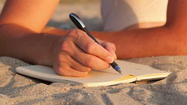 Man writing in his diary at the beach