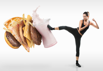 Fit young woman fighting off fast food - obrazy, fototapety, plakaty