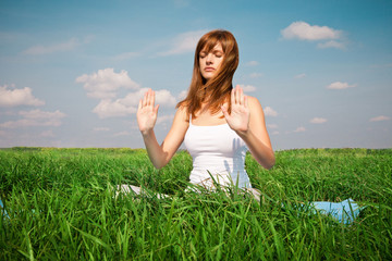Young girl doing yoga (lotus pose) in the park