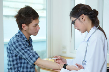 Obraz premium Young woman doctor giving male patient injection