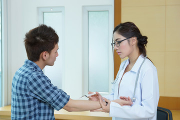 Young woman doctor giving male patient injection