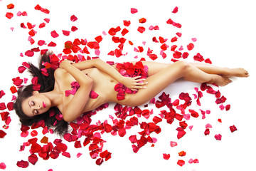 slim woman lying on red roses petals over white