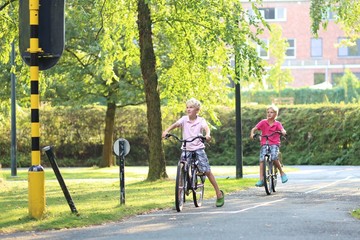 Obraz premium Two twin brothers riding bicycles stopping at red lights