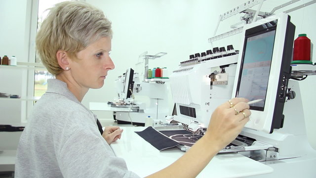 Female engineer working on computerized machine embroidery