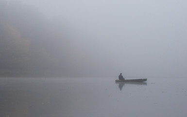 Fisherman on small boat on foggy morning
