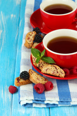 Cups of tea with cookies and berries on table close-up
