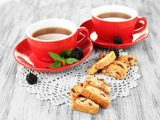 Cups of tea with cookies and blackberry on table close-up