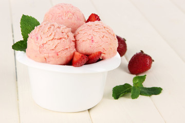 Tasty ice cream scoops in bowl, on wooden table