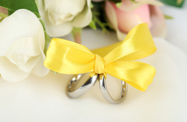 Wedding rings tied with ribbon on white fabric