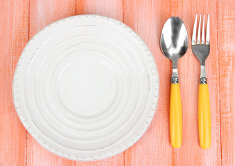 Plate and cutlery on wooden table close-up