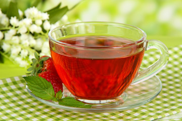 Delicious strawberry tea on table on bright background