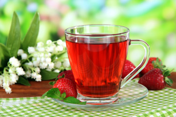 Delicious strawberry tea on table on bright background