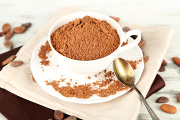 Cocoa powder in cup on napkin on wooden table