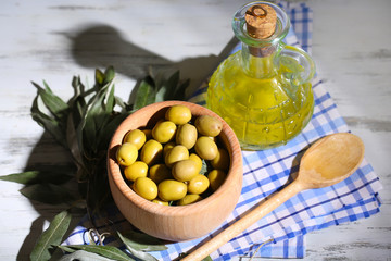 Olive oil and olives in bowl on on napkin wooden table