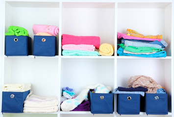 Blue textile boxes with towels and clothes in white shelves