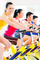 Fototapeta premium Asian people in spinning bike training at fitness gym