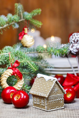 Gingerbread house by the fir branch on christmas eve table