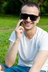 Naklejka na ściany i meble Young man speaks on the phone on the grass