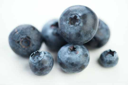 Macro shot of blueberries over white wooden background