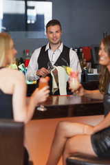 Handsome bartender working while gorgeous friends talking