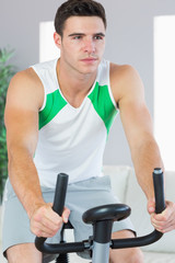 Fototapeta na wymiar Unsmiling handsome man training on exercise bike