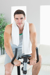 Fototapeta na wymiar Happy handsome man training on exercise bike