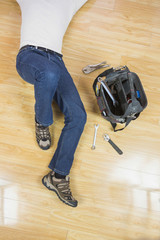 Close up of male legs lying on floor next to tool kit