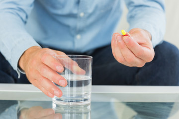 Close up of man holding glass of water and pill
