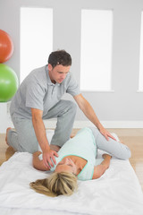 Fototapeta premium Physiotherapist examining patients hips on a mat on the floor