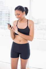 Concentrated dark haired model in sportswear using a mobile phon