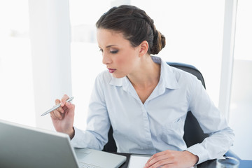 Focused stylish brunette businesswoman pointing her laptop with