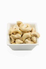 Isolated cashews in white dish on white background