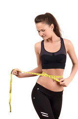 Fit girl measuring her waist with a measuring tape in inch