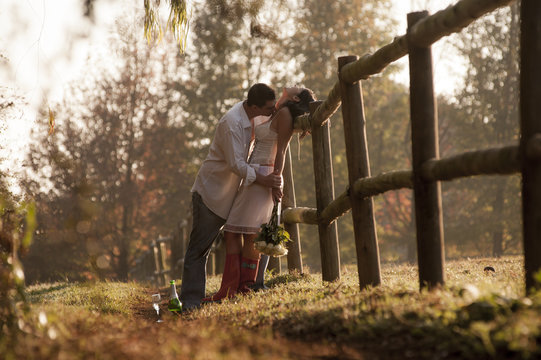 Young attractive couple leaning on wooden fence kissing